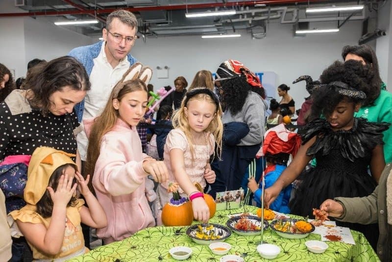 Children in costumes decorating pumpkins at a Brooklyn Bridge Parents fest at City Point