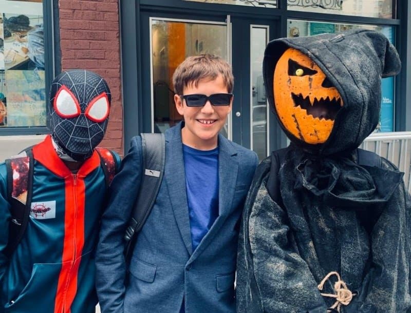 Three kids in Halloween costumes on a Brooklyn sidewalk