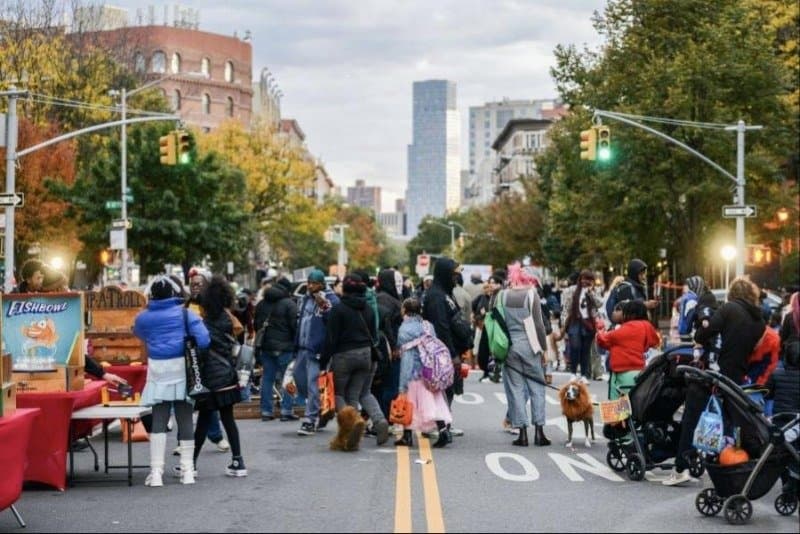 Kids and adults in Halloween costumes on a street closed to